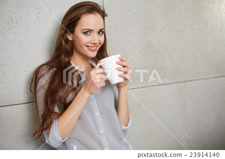 woman sitting on the couch with a cup 23914140