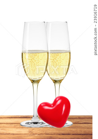 Two glasses of champagne and red heart on table 23916719