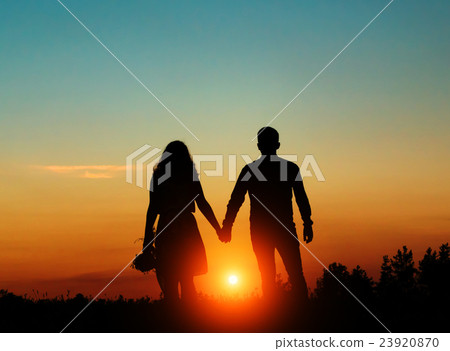 Silhouetted loving couple at sunset 23920870