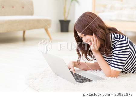 A woman watching a computer in a room 23921872