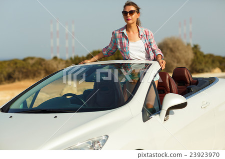 Beautiful woman sitting in cabriolet, enjoying trip on luxury mo 23923970