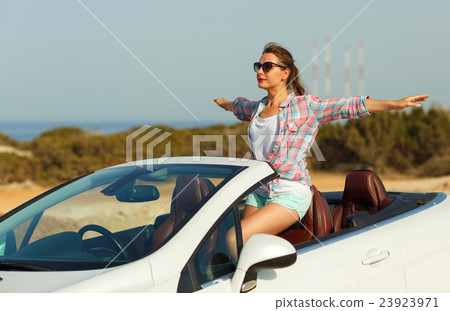 Beautiful woman sitting in cabriolet, enjoying trip on luxury mo 23923971