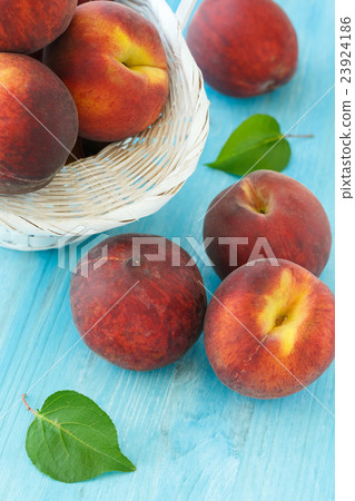 Ripe peaches in basket on wooden background 23924186