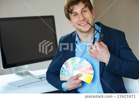 Man looking to a color paint palette at office 23925971