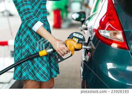 Woman fills petrol into her car at a gas station Woman fills petrol into her car at a gas station 23926193