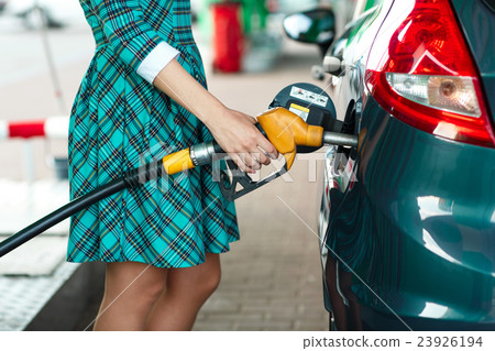 Woman fills petrol into her car at a gas station 23926194