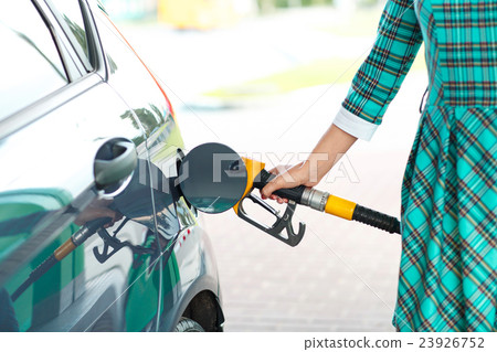 Woman fills petrol into her car at a gas station Woman fills petrol into her car at a gas station 23926752