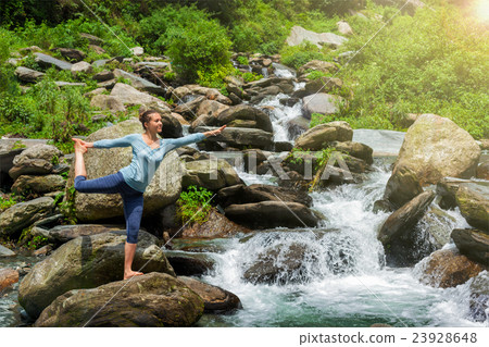 Woman doing yoga asana Natarajasana outdoors at 23928648