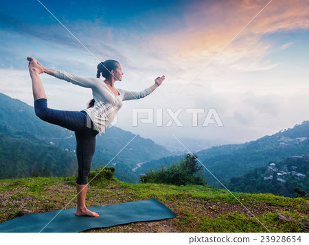 Woman doing yoga asana Natarajasana outdoors at 23928654