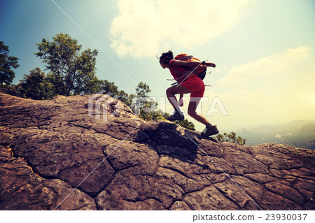 youngwoman hiker climbing on mountain peak cliff 23930037