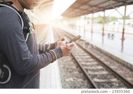 man holding smartphone backpack at train station man holding smartphone backpack at train station 23935360