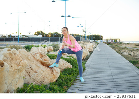 Woman resting after jogging on a wooden path at the sea Woman resting after jogging on a wooden path at the sea 23937631