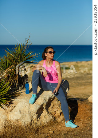 Girl resting after jogging on the rock at the sea Girl resting after jogging on the rock at the sea 23938054