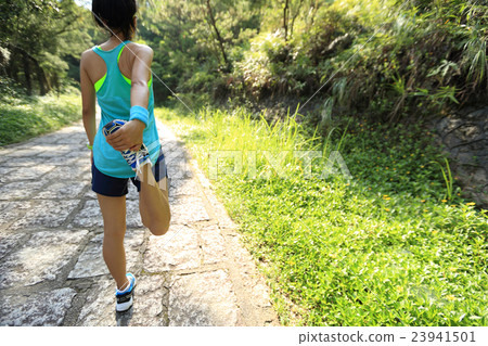 young woman trail runner warm up on country road 23941501