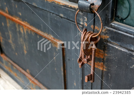 some old and rusty keys chain on a rustic door 23942385