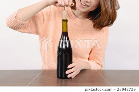 A young woman who opens a wine cork A young woman who opens a wine cork 23942729