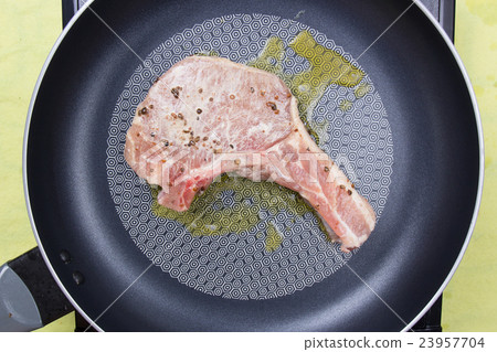 Chef cooking porkchop in frying pan Chef cooking porkchop in frying pan 23957704