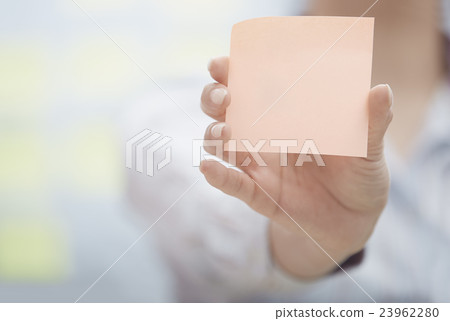 Hand of woman holding sticky note with empty space 23962280