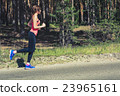 Young fitness woman running on forest trail 23965161