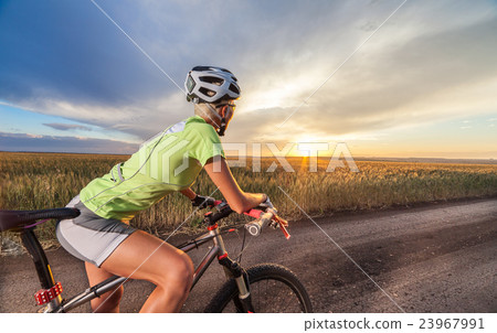 Biker on the meadow at the sunset against blue sky 23967991