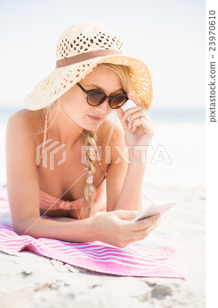 Pretty woman in bikini and sunglasses using mobile phone on the 23970610