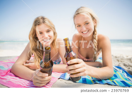 Happy women lying on the beach with beer bottle Happy women lying on the beach with beer bottle 23970769