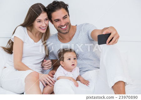 Happy family clicking selfie on bed 23970890