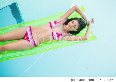 Beautiful woman in bikini lying on air bed in swimming pool 23970936