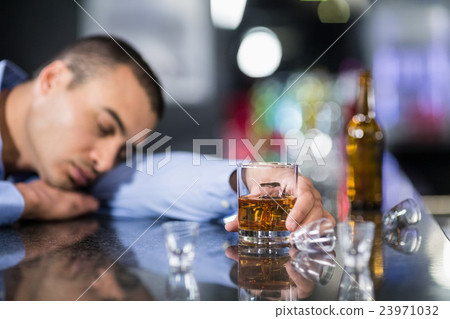 Tired man having a whiskey and sleeping on a counter Tired man having a whiskey and sleeping on a counter 23971032