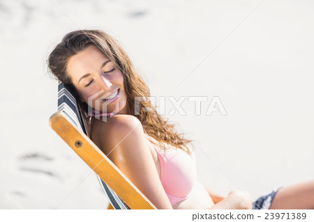 Happy woman sitting on an armchair with eyes closed 23971389