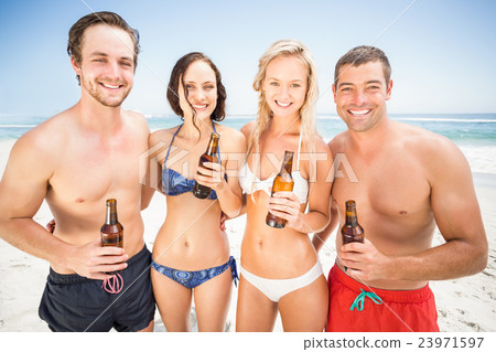 Portrait of happy friends standing on the beach with beer bottle Portrait of happy friends standing on the beach with beer bottle 23971597
