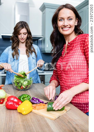 Happy female friends preparing salad 23972003
