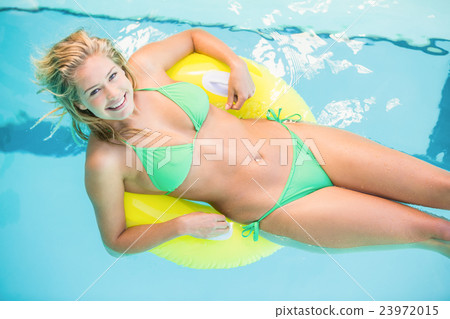 Beautiful woman in green bikini relaxing on inflatable tube in s 23972015