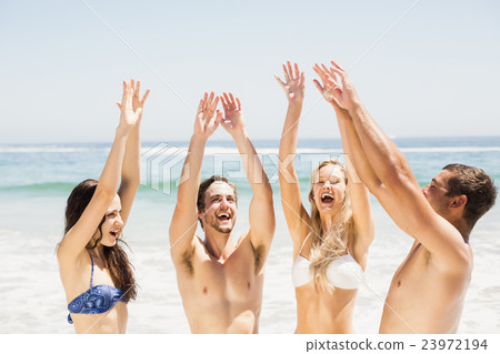 Happy friends raising their hands on the beach 23972194