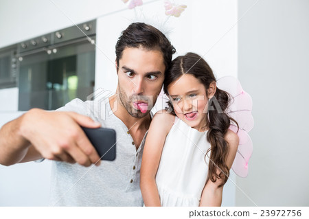 Father and daughter making faces while taking self portrait 23972756