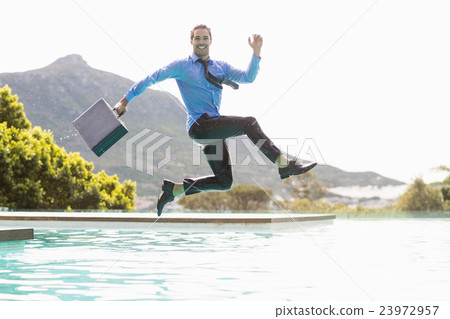 Businessman jumping over swimming pool 23972957