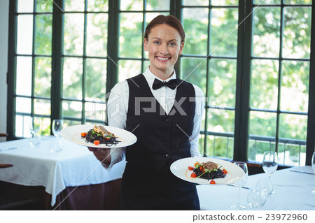 Smiling waitress holding plates Smiling waitress holding plates 23972960