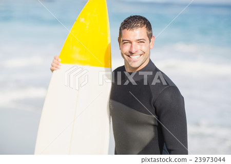 Portrait of happy man holding a surfboard on the beach Portrait of happy man holding a surfboard on the beach 23973044