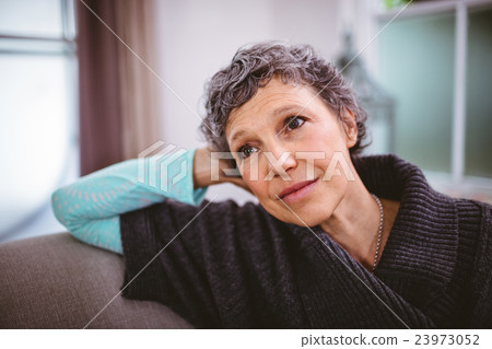 Thoughtful mature woman sitting on sofa 23973052