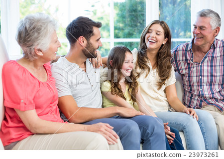 Multi-generation family smiling while sitting on sofa Multi-generation family smiling while sitting on sofa 23973261