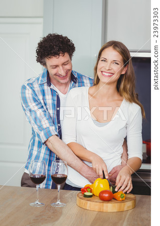 Portrait of smiling wife with husband in kitchen Portrait of smiling wife with husband in kitchen 23973303