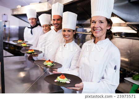 Happy chefs presenting their food plates Happy chefs presenting their food plates 23973571