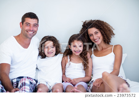 Portrait of a family sitting together on bed Portrait of a family sitting together on bed 23973572