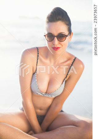 Glamorous woman in bikini sitting on the beach Glamorous woman in bikini sitting on the beach 23973657