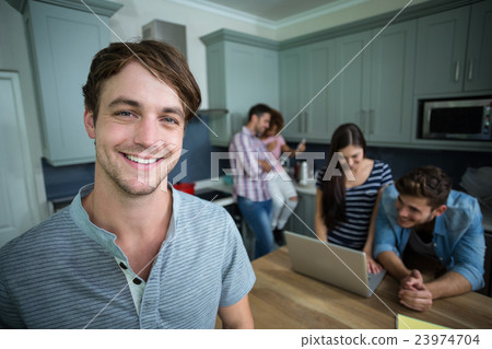 Portrait of happy man with friends in background at home 23974704