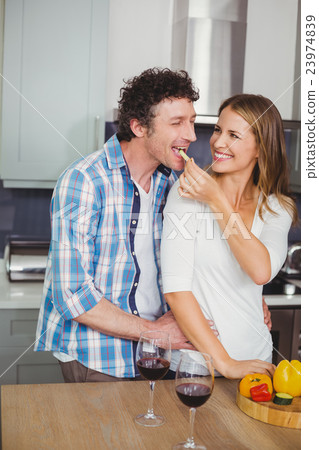 Smiling beautiful wife feeding husband in kitchen 23974839