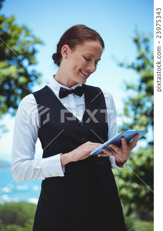 Smiling waitress taking an order with a tablet 23975343