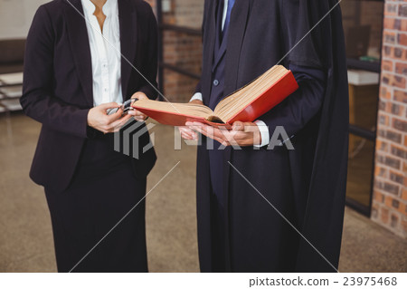 Male lawyer with female colleague discussing over book 23975468
