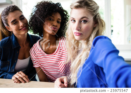 Portrait of beautiful young female friends puckering lips Portrait of beautiful young female friends puckering lips 23975547