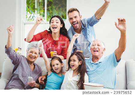 Family cheering while watching television Family cheering while watching television 23975652